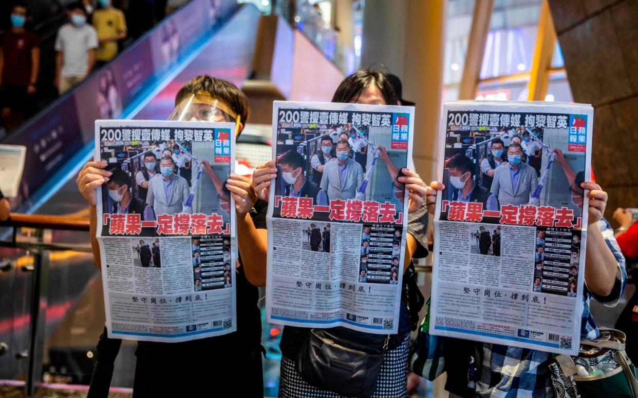 People hold up copies of the Apple Daily as they protest for press freedom inside a mall in Hong Kong  - AFP