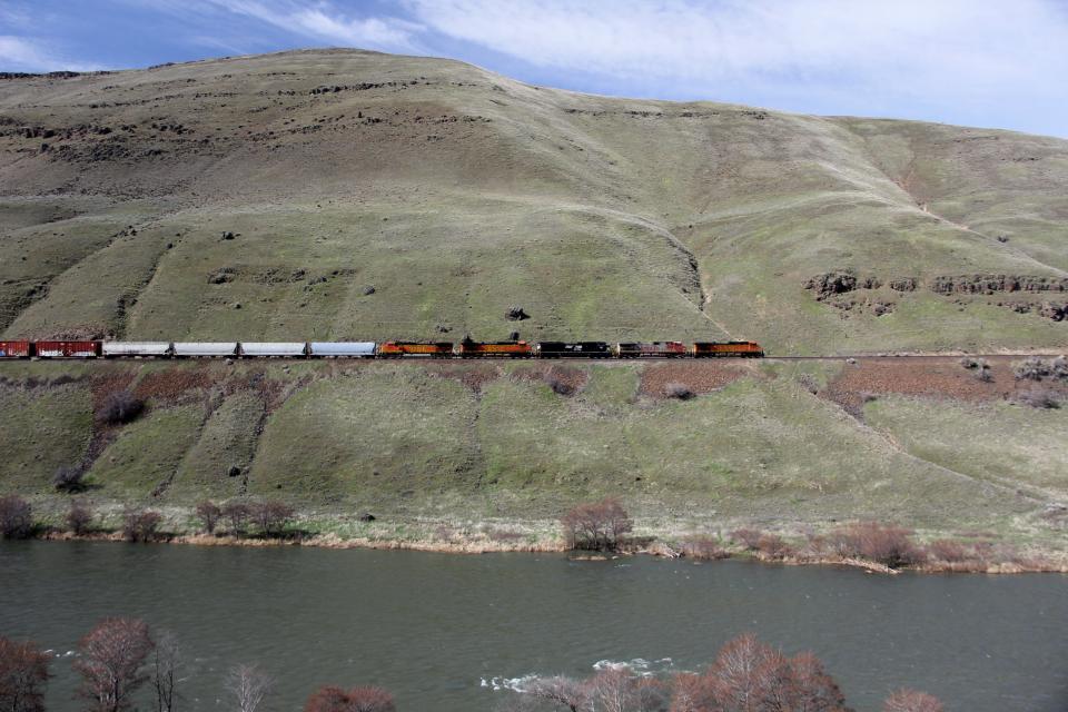 A train runs along the tracks in the Lower Deschutes River canyon.