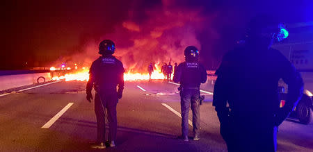 Police officers stand next to burning barricades settled to block the AP7 highway during a regional strike near Girona, Spain, February 21, 2019. REUTERS/Pilar Suarez