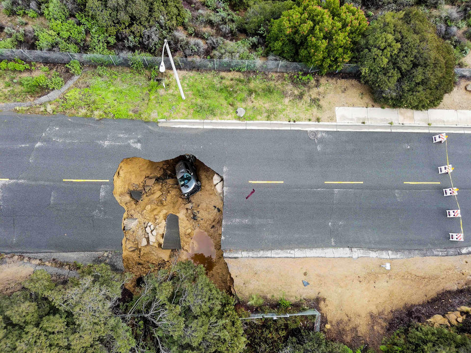 Image: Two cars siting in a large sinkhole that opened during a day of relentless rain, Jan. 10, 2023 in the Chatsworth neighborhood of Los Angeles. (Robyn Beck / AFP - Getty Images)