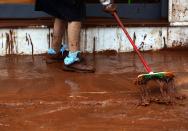 <p>A woman sweeps mud outside her house at Mandra, Attica region, Greece, Nov. 16, 2017. (Photo: Simela Pantzartzi/EPA-EFE/REX/Shutterstock) </p>