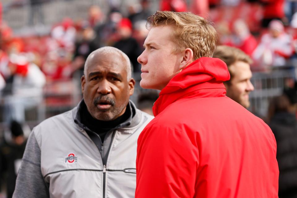 Football recruit Devin Brown, a quarterback from Corner Canyon High School in Utah, walks onto the field with Ohio State Buckeyes athletics director Gene Smith and quarterbacks coach Corey Dennis prior to the game against the Michigan State Spartans at Ohio Stadium in Columbus on Saturday, Nov. 20, 2021. 