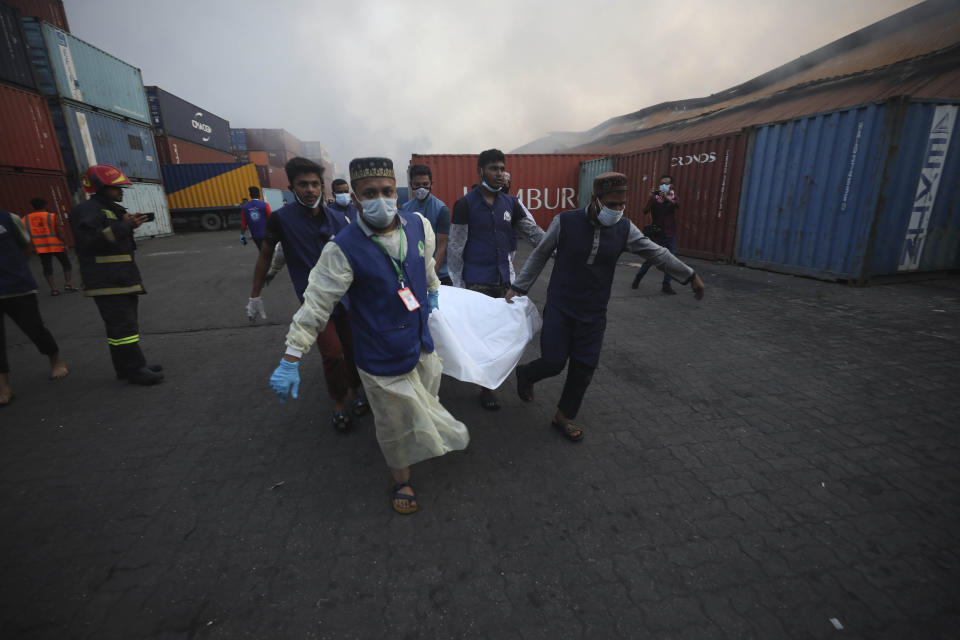 Gente trasladando el cuerpo de una víctima de un incendio en el BM Inland Container Depot, un depósito con participación holandesa y bangladeshí, en Chittagong, 216 kilómetros (134 millas) al sureste de la capital, Daca, Bangladesh, el domingo 5 d ejunio de 2022. (AP Foto)