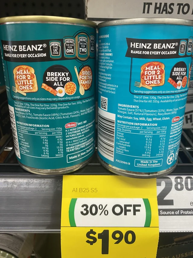 Two cans of Kraft Heinz baked beans on a shelf showing alleged shrinkflation.