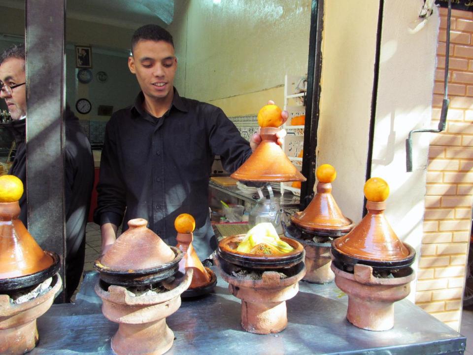 This January 2013 photo shows tagines, or meat and vegetables stews, cooking outside the Chez el Bahia restaurant in the historic medina of Marrakech, Morocco. The fragrant scents of rich spices from Moroccan cuisine pervade the historic centers. (AP Photo/Giovanna Dell'Orto)