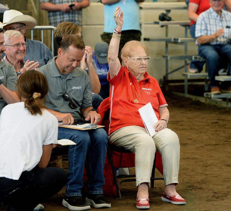 Evelyn Brandt Thomas, of Springfield, raises a hand in triumph after winning the bid for the Land of Lincoln Grand Champion Steer during the Governor's Sale of Champions at the Illinois State Fair Wednesday, August 16, 2023. The audience serenaded Brandt Thomas with "Happy Birthday," in advance of her 100th birthday Aug. 25.