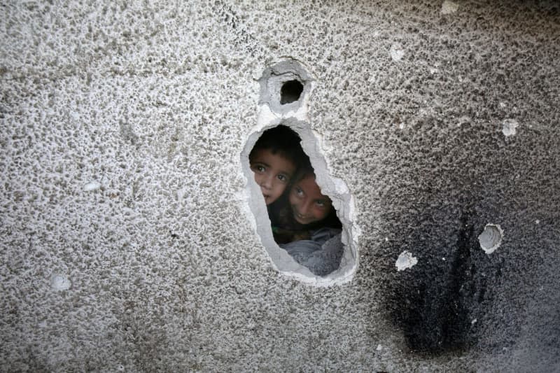 Palestinian children look through bullet holes after an Israeli airstrike on a school for displaced persons of the United Nations Relief and Works Agency for Palestine Refugees in the Near East (UNRWA) in the Nuseirat refugee camp.  Omar Ashtawy/APA Images via ZUMA Press Wire/dpa