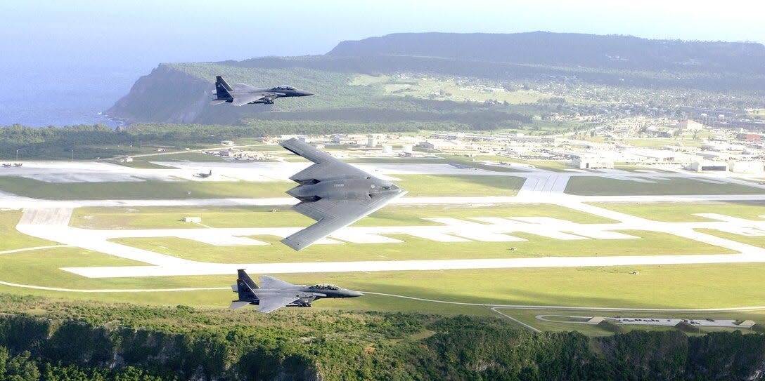 F-15E Strike Eagles and a B-2 Spirit bomber fly in formation over Andersen Air Force Base on Guam