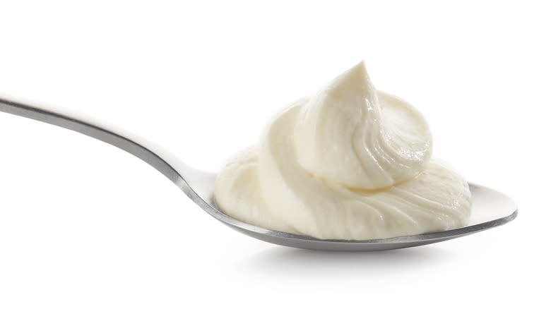 Cream cheese on spoon on white background