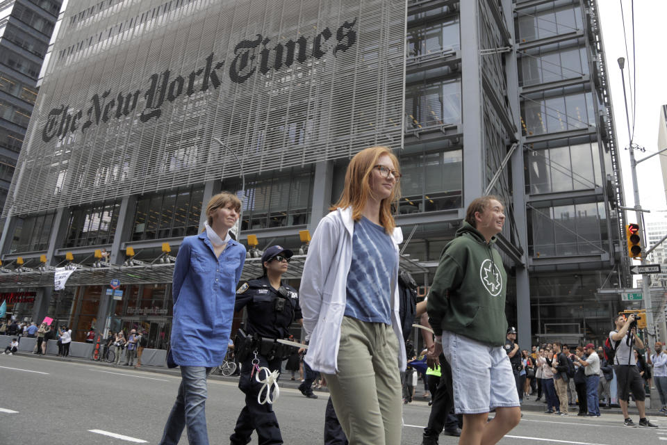 Activists are taken into custody by New York Police officers during a climate change rally outside of the New York Times building, Saturday, June 22, 2019, in New York. Activists blocked traffic along 8th Avenue during a sit-in to demand coverage of climate change by the newspaper. (AP Photo/Julio Cortez)