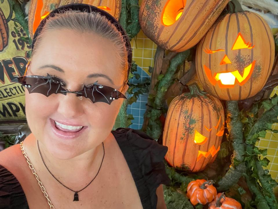 carly wearing bat sunglasses posing in front of pumpkins at halloween horror nights