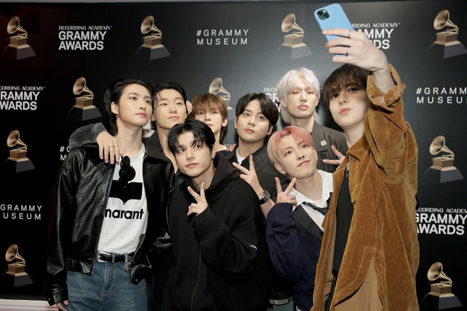 (L-R back row) Seong-hwa, San, Kang Yeo-sang, Choi Jong-ho, Song Min-gi, (L-R front) Woo-young, Kim Hong-joong, and Jeong Yun-ho of ATEEZ take a selfie at ATEEZ ribbon cutting at GRAMMY Museum L.A. Live on April 18, 2024 in Los Angeles, California.