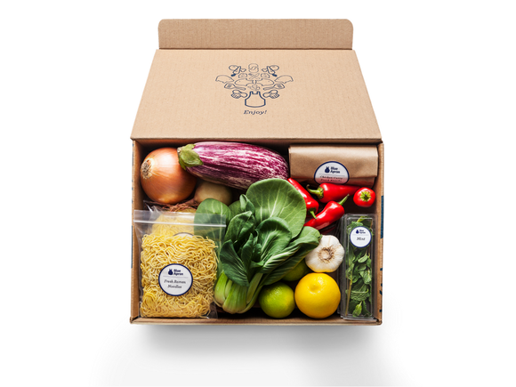 A box of ingredients from Blue Apron, including several vegetables and noodles