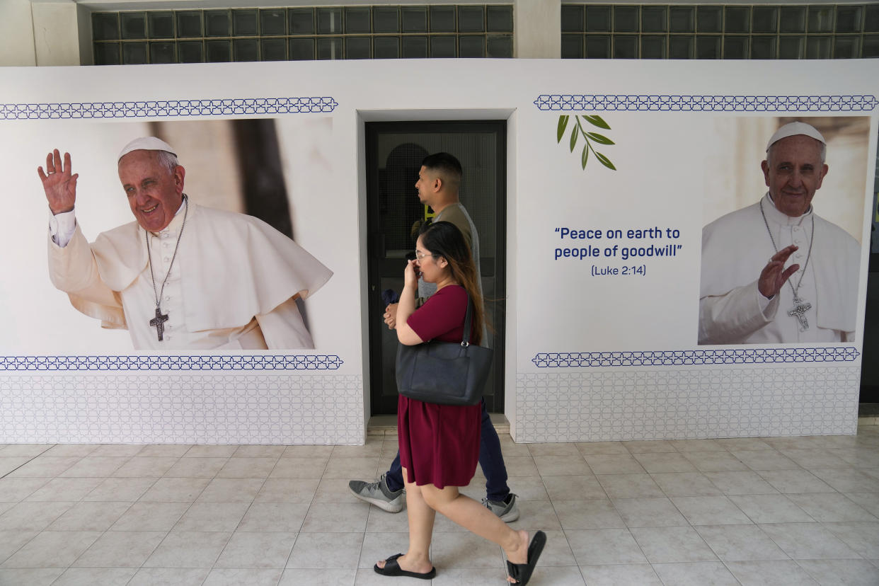 A couple passes portraits of Pope Francis at Sacred Heart church in Manama, Bahrain, Wednesday, Nov. 2, 2022. Pope Francis is making the Nov. 3-6 visit to participate in a government-sponsored conference on East-West dialogue and to minister to Bahrain's tiny Catholic community, part of his effort to pursue dialogue with the Muslim world. (AP Photo/Hussein Malla)