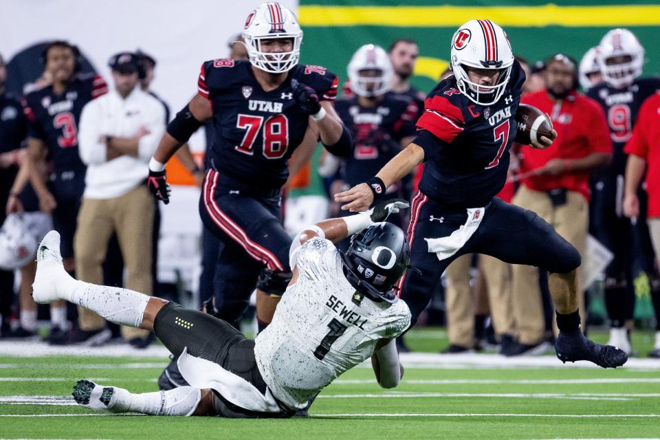 Utah quarterback Cam Rising evades the tackle of Oregon linebacker Noah Sewell during the Pac-12 championship game.