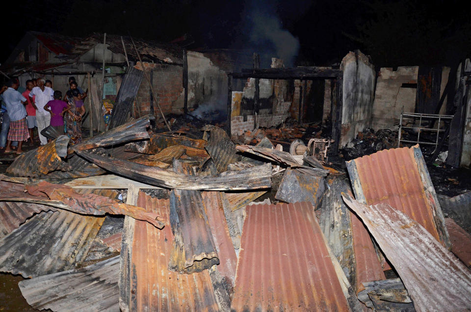 People stand next to burnt shops in Assam