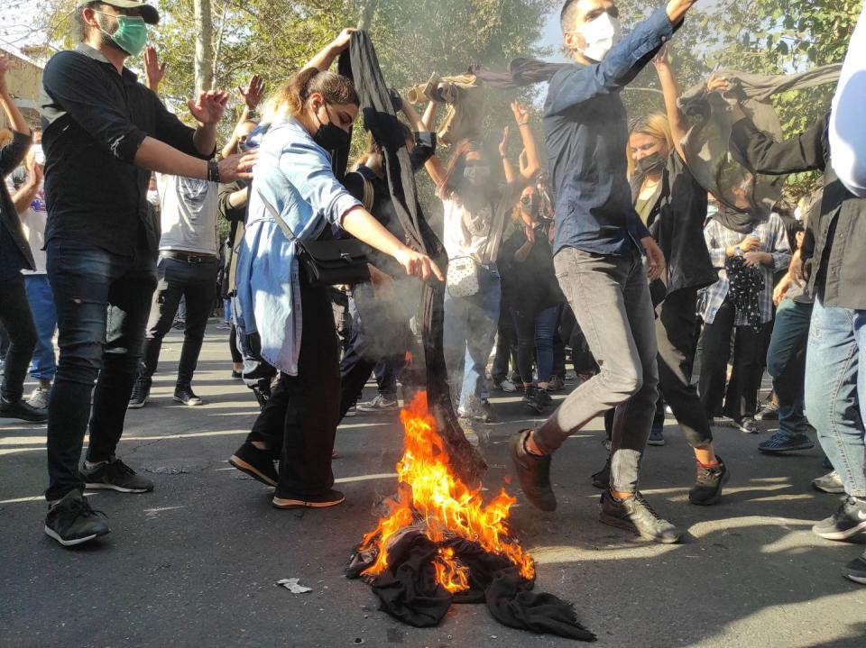 tehran, iran october 01 iranian protesters set their scarves on fire while marching down a street on october 1, 2022 in tehran, iran protests over the death of 22 year old iranian mahsa amini have continued to intensify despite crackdowns by the authorities, the 22 year old iranian fell into a coma and died after being arrested in tehran by the morality police, for allegedly violating the countries hijab rules photo by getty images