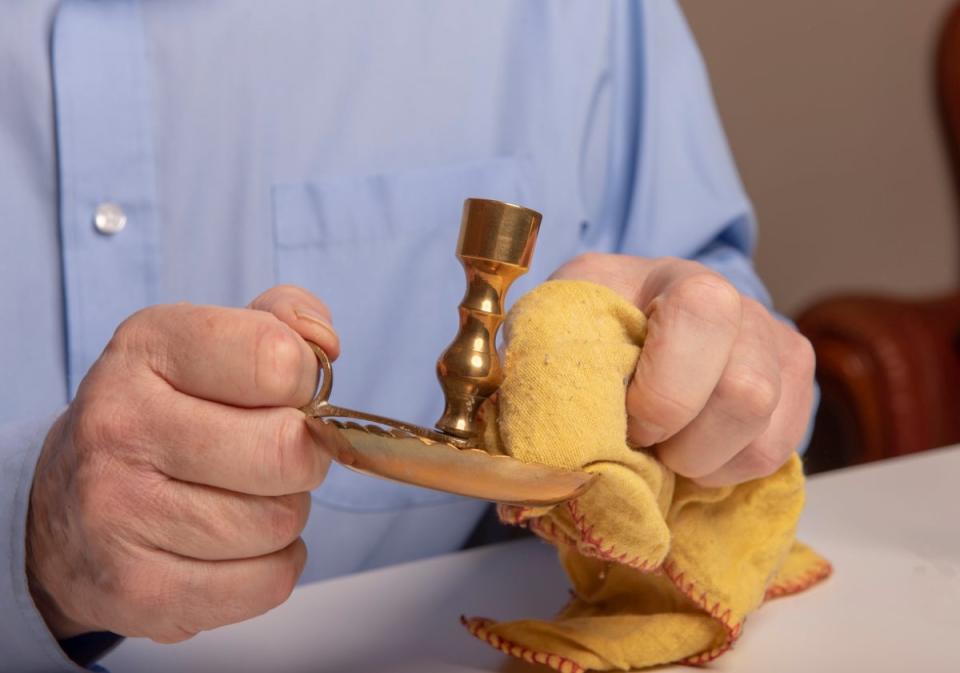 Man using microfiber towel to clean brass candlestick