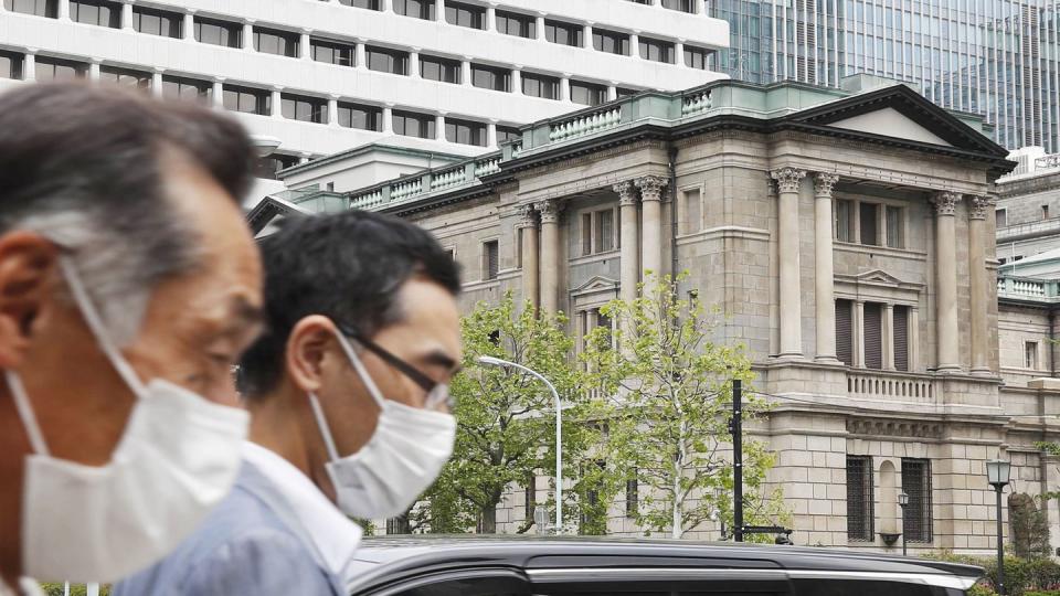 Menschen gehen mit Gesichtsmasken am Gebäude des Hauptsitzes der «Bank of Japan» (BoJ) in Tokio vorbei.