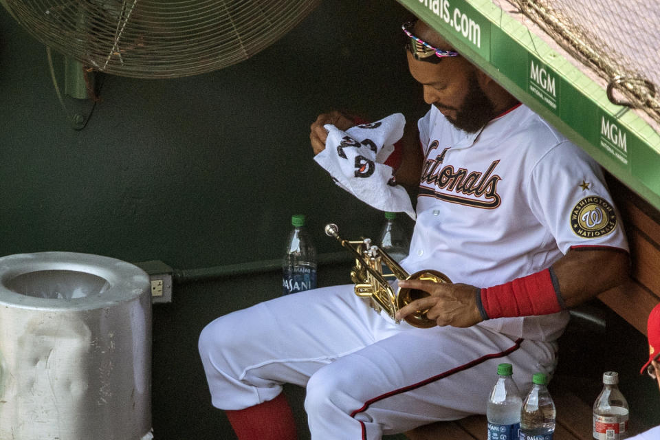 Washington Nationals' Emilio Bonifacio wipes his trumpet in the dugout during a baseball game against the New York Yankees at Nationals Park, Sunday, July 26, 2020, in Washington. (AP Photo/Alex Brandon)