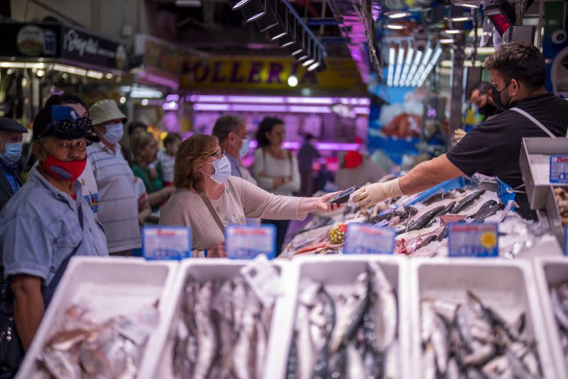 A customer pays for fish at the Maravillas market in Madrid, on May 12, 2022. 