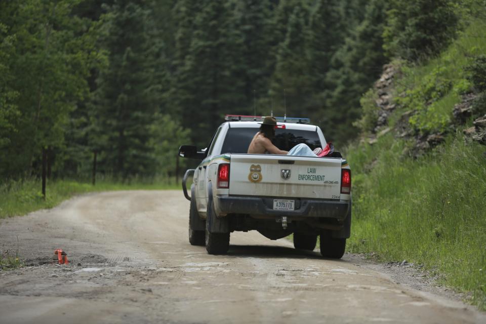 Physician John Hartberg, left, tends to a elderly patient in a Forest Service pickup truck Friday, July 2, 2021, in the Carson National Forest, outside of Taos, N.M.. Hartberg, from New Orleans, was attending the annual hippie gathering when the man fell ill and volunteered to help get him to a helicopter at the nearest paved road. The condition of the man was not immediately known. (AP Photo/Cedar Attanasio)
