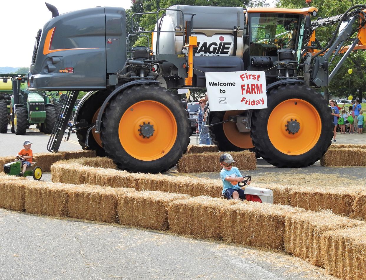 Children ride a pedal tractor through a corn maze in front of a large piece of farm machinery at the First Farm Friday event in 2021. The event returns on Friday with a concert by ERNEST following.