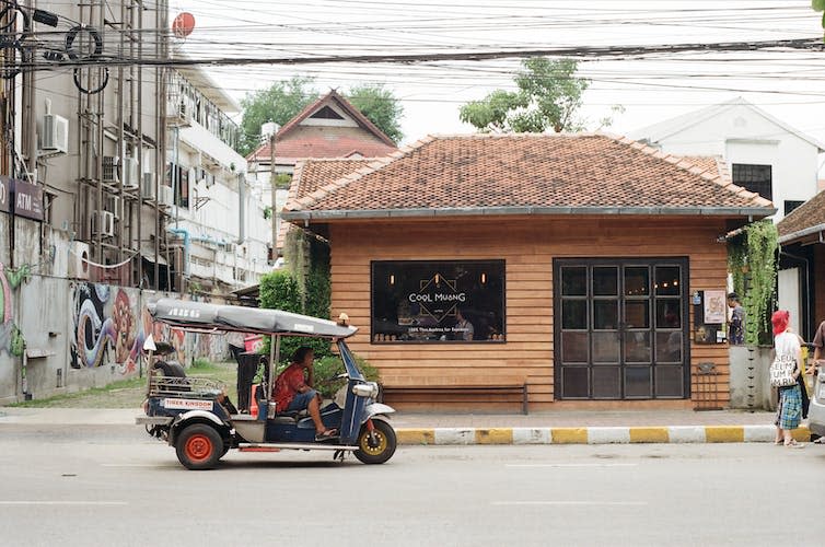 A coffee shop and a small vehicle in a Thai city.