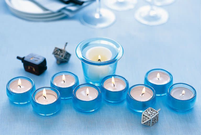 <p>Try this modern take on the menorah. Use tealights in blue holders to represent each of the eight days and one larger holder to serve as the shamash candle.</p><p><em><a href="https://www.goodhousekeeping.com/holidays/how-to/a16025/menorah-candle-craft/" rel="nofollow noopener" target="_blank" data-ylk="slk:Get the tutorial;elm:context_link;itc:0;sec:content-canvas" class="link ">Get the tutorial</a></em></p>