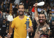Richard Gasquet of France poses with the trophy with a local Maori perfomer after winning the men's singles final over Cameron Norrie of Britain at the ASB Classic tennis event in Auckland, New Zealand, Saturday, Jan. 14, 2023. (Andrew Cornaga/Photoport via AP)