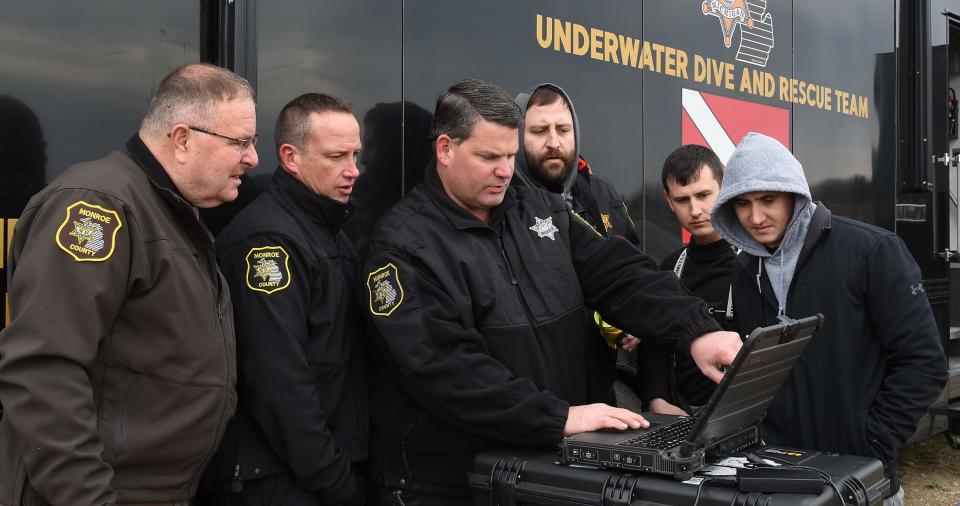 Monroe County Sheriff Troy Goodnough, left, Lt. Brian Francisco, Deputy Dave Moore, Detective Josh Motylinski, Deputy Steve Warren and Deputy Mike Stahl take a close look on the computer screen of what their new Kongsberg MS 1000 360-degree sonar machine was showing under the water at Lake Monroe, the former quarry in Monroe Charter Township.