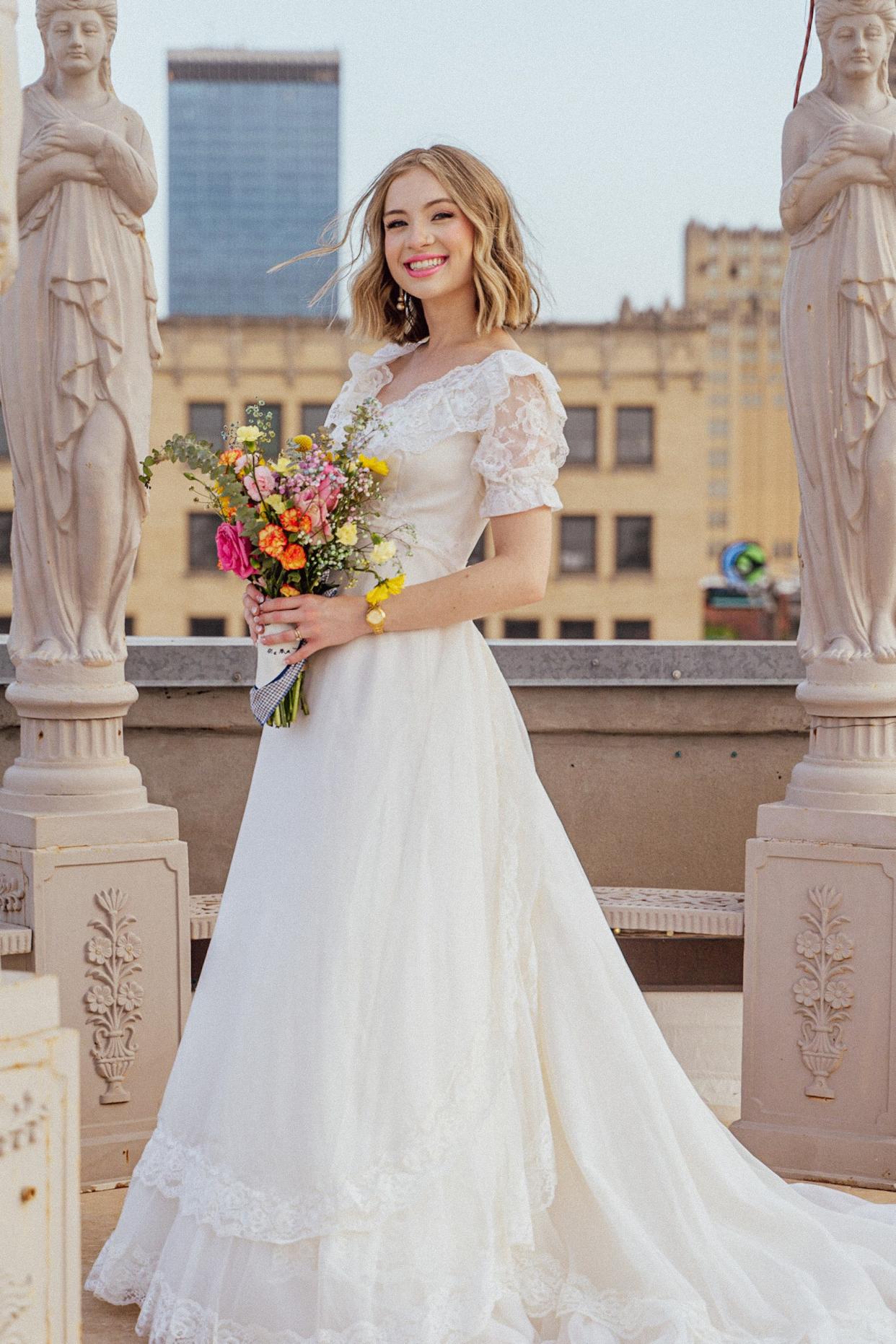 A bride smiles in her wedding dress in the middle of statues.