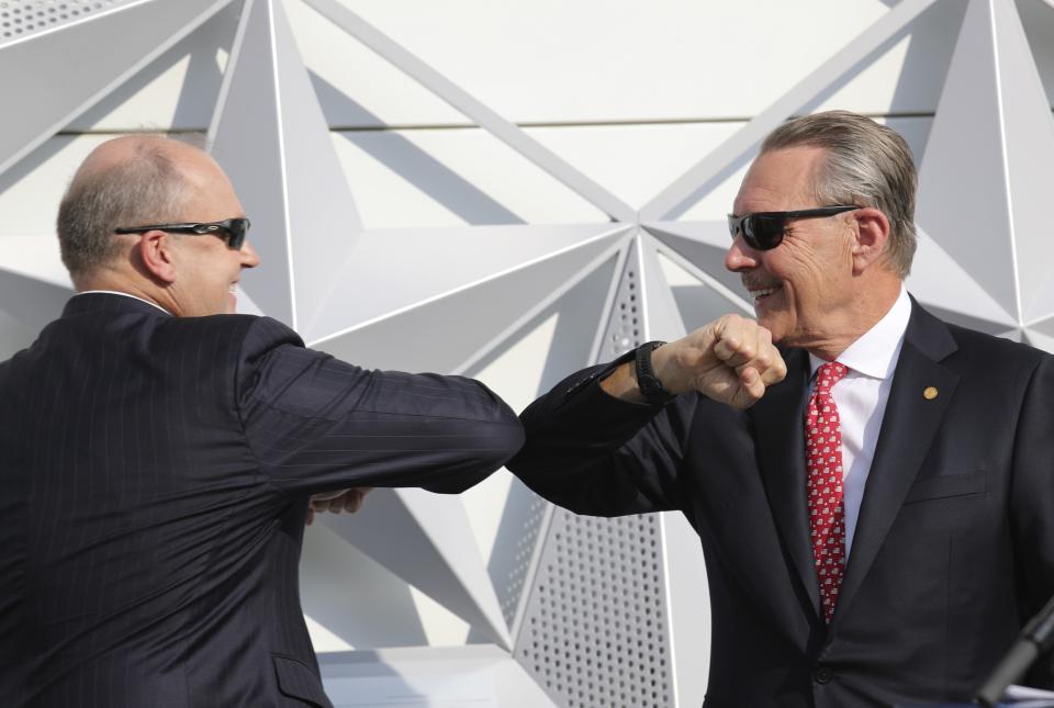 U.S. Ambassador John Rakolta, right, and U.S. State Department Counselor Ulrich Brechbuhl, touch elbows after they fixed the last piece of star on the elevation during the U.S.A Pavilion handover ceremony at the Dubai Expo 2020, United Arab Emirates, Wednesday, Nov. 18, 2020. The U.S. showed off a literally star-studded pavilion Wednesday for Dubai's upcoming Expo 2020, complete with a replica SpaceX rocket body beside it. (AP Photo/Kamran Jebreili)