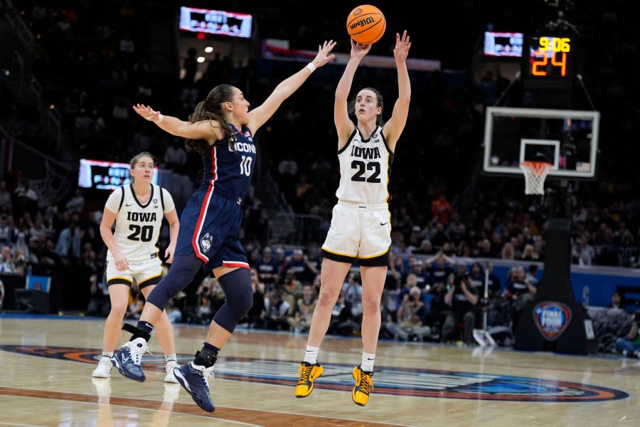 Iowa guard Caitlin Clark (22) shoots a three-point basket over UConn guard <a class="link " href="https://sports.yahoo.com/ncaaw/players/64083/" data-i13n="sec:content-canvas;subsec:anchor_text;elm:context_link" data-ylk="slk:Nika Muhl;sec:content-canvas;subsec:anchor_text;elm:context_link;itc:0">Nika Muhl</a> (10) during the second half of a Final Four college basketball game in the women’s NCAA Tournament, Friday, April 5, 2024, in Cleveland. (AP Photo/Morry Gash)