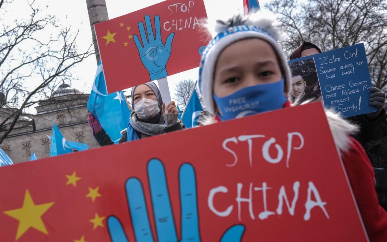 Uyghur protestors who have not heard from their families living in East Turkestan hold placards and Uyghur flags during a protest against China, in Istanbul -  SEDAT SUNA/Shutterstock 