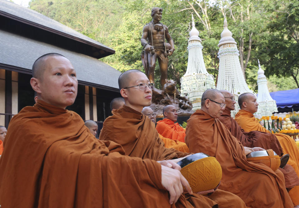 Thai Buddhist monks sit in front of the statue of Saman Gunan, the retired Thai SEAL diver who died during the rescue mission of a trapped soccer team, near the Tham Luang cave in Mae Sai, Chiang Rai province, Thailand Monday, June 24, 2019. The 12 boys and their coach attended a Buddhist merit-making ceremony at the Tham Luang to commemorate the one-year anniversary of their ordeal that saw them trapped in a flooded cave for more than two weeks. (AP Photo/Sakchai Lalit)