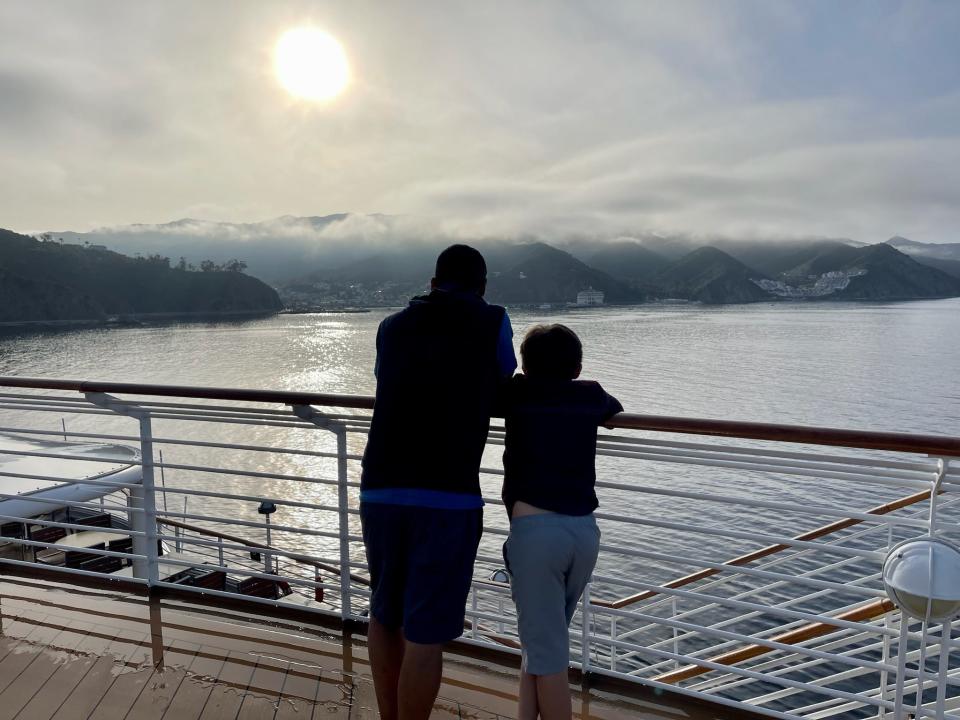 The author's tween son and his father looking over the railing of a cruise ship balcony at the sun