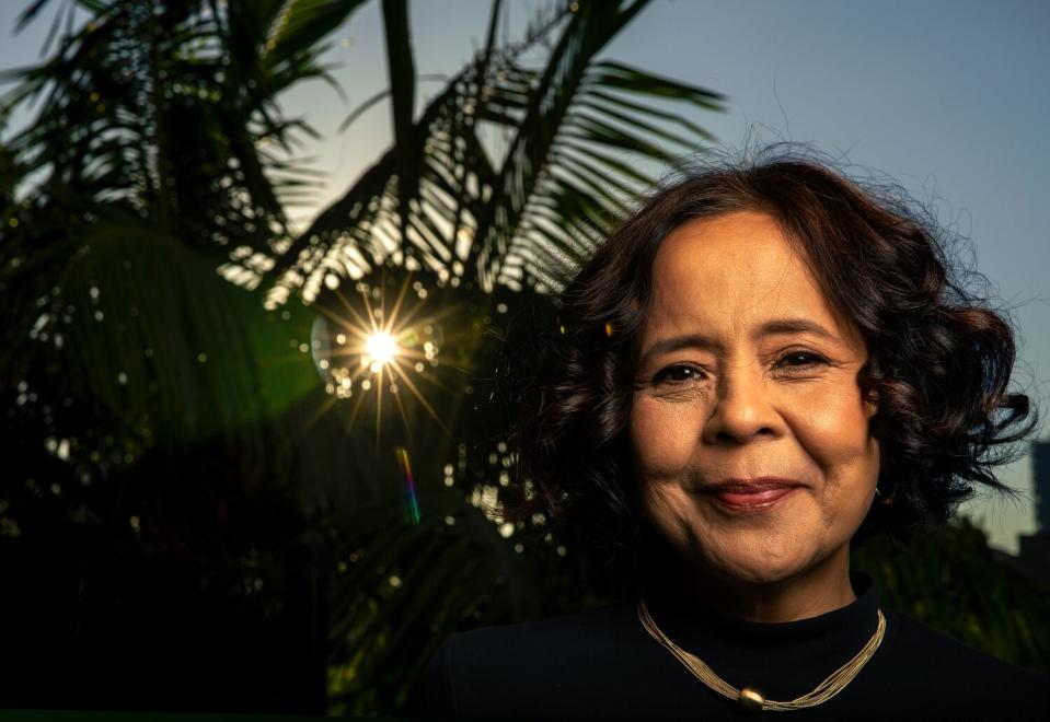 A smiling woman next to palm fronds.