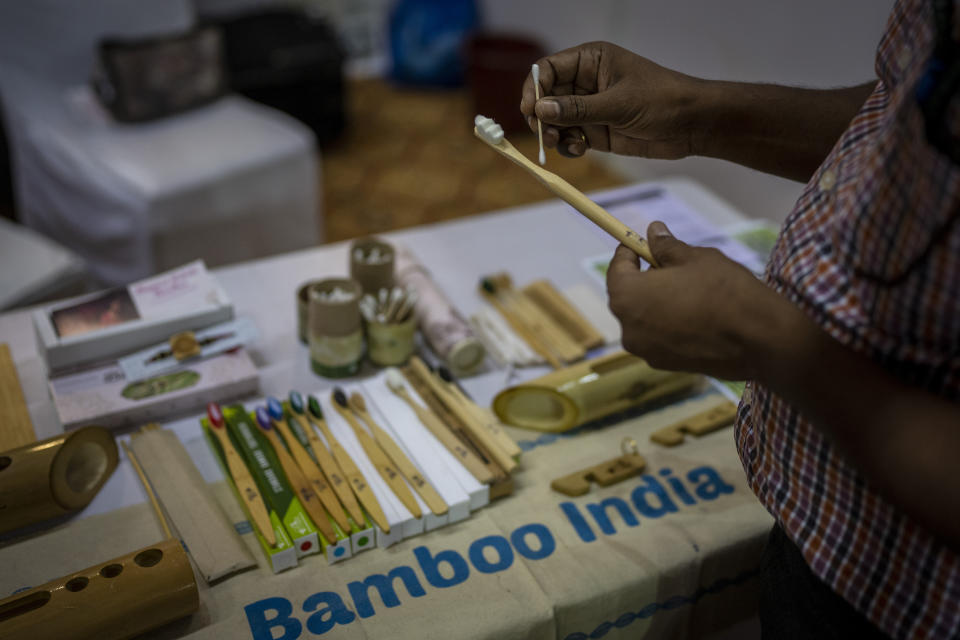 A visitor looks at earbuds and a toothbrush made of bamboo at an event to create awareness about eco-friendly products in New Delhi, India, Friday, July 1, 2022. India banned some single-use or disposable plastic products Friday as part of a federal plan to phase out the ubiquitous material in the nation of nearly 1.4 billion people. (AP Photo/Altaf Qadri)