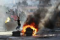 A Palestinian youth uses a slingshot to throw stones at Israeli security forces during clashes at the main entrance of the West Bank town of Bethlehem on October 6, 2015