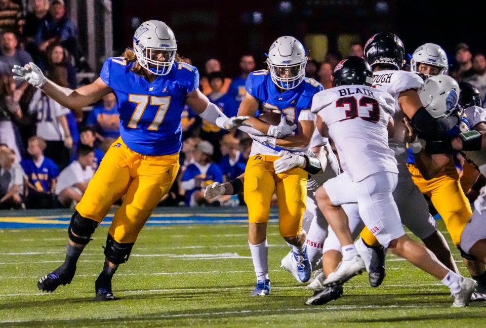 Mukwonago lineman Nathan Roy (77) makes a hole for running back Wynn Stang (21) during the game at home against Muskego on Friday, Sept. 16, 2022.