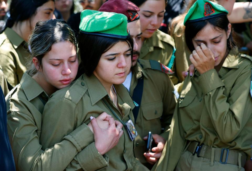 Israeli women in military uniforms embrace and weep