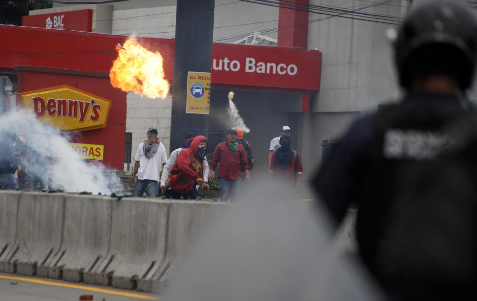 A man throws a molotov cocktail at the police during a protest against the government of Honduras' President Juan Orlando Hernandez in Tegucigalpa, Honduras, Thursday, May 30, 2019. Thousands of doctors and teachers have been marching through the streets of Honduras' capital for the last three weeks, against presidential decrees they say would lead to massive public sector layoffs. (AP Photo/Elmer Martinez)