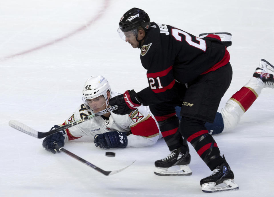 Florida Panthers defenseman Gustav Forsling (42) knocks the puck away from Ottawa Senators right wing Mathieu Joseph (21) as he slides on the ice during first-period NHL hockey game action in Ottawa, Ontario, Monday, Nov. 27, 2023. (Adrian Wyld/The Canadian Press via AP)