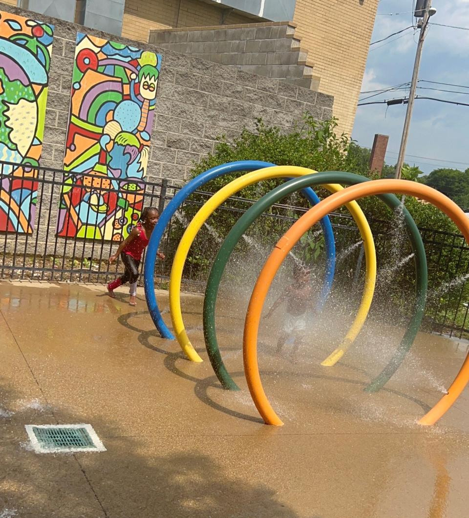 Erionna and her baby brother Amir running through the water jets of Kirkpatrick's splash pad.