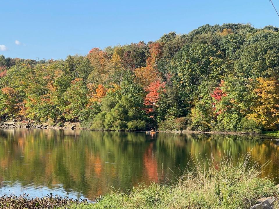 The colors of fall are reflected in the water at the Quemahoning Reservoir, near Hollsopple, while a man in a kayak fishes near the shoreline.