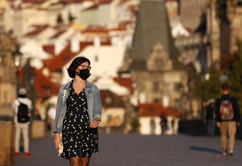 A young woman wearing a face mask walks across the medieval Charles Bridge in Prague, Czech Republic, Friday, Sept. 18, 2020. The Czech Republic has been been facing the second wave of infections. The number of new confirmed coronavirus infections has been setting new records almost on a daily basis, currently surpassing 3,000 cases in one day for the first time. (AP Photo/Petr David Josek)