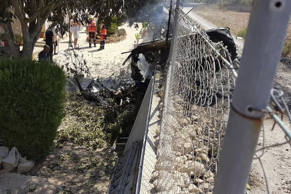 This photo provided by Incendios f.Baleares shows wreckage by a fence near Inca in Palma de Mallorca, Spain, Sunday Aug. 25, 2019. Authorities in Mallorca say at least 5 people have died in a collision between a helicopter and a light plane on the Spanish island. (Incendios f.Baleares Via AP)