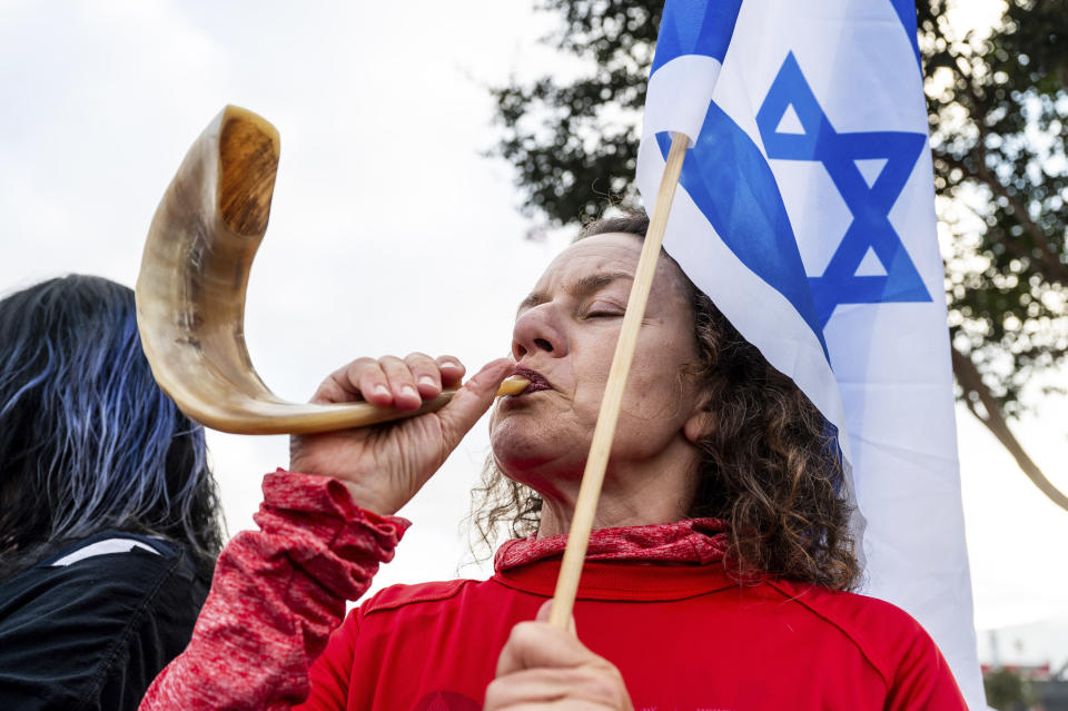 Elizabeth Lichy, uses a ceremonial ram's horn, while protesting outside Tesla's Fremont, Calif., factory as Israeli Prime Minister Benjamin Netanyahu plans a visit with businessman Elon Musk on Monday, Sept. 18, 2023. (AP Photo/Noah Berger)