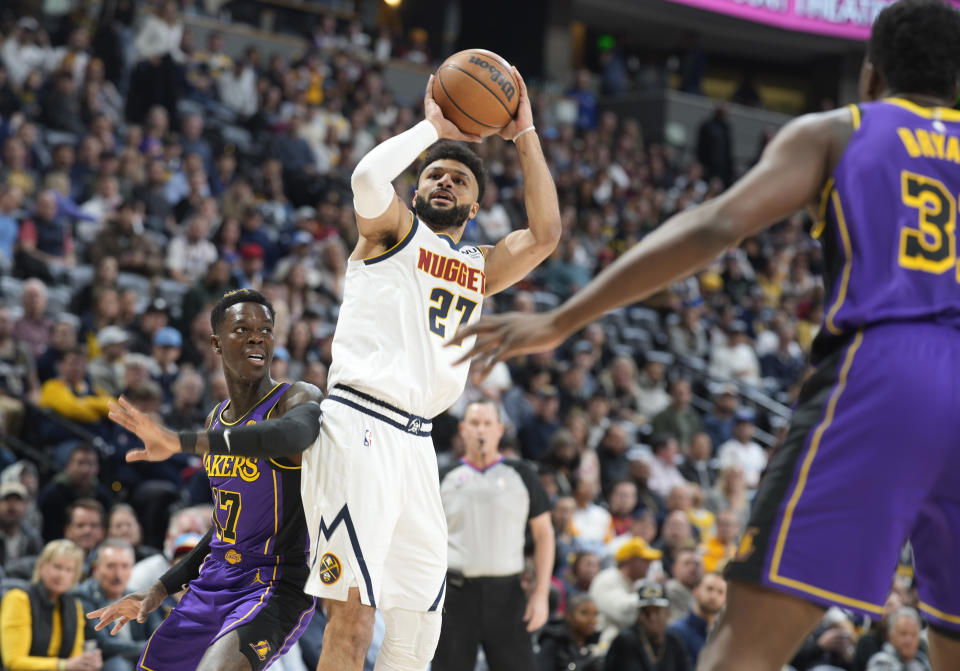 Denver Nuggets guard Jamal Murray, center, goes up to shoot between Los Angeles Lakers guard Dennis Schroder, left, and center Thomas Bryant in the first half of an NBA basketball game Monday, Jan. 9, 2023, in Denver. (AP Photo/David Zalubowski)